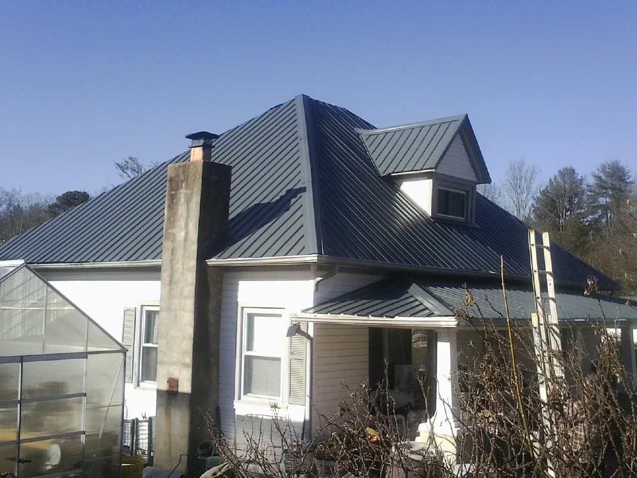 Dark blue standing seam metal roof on a white farmhouse with dormer — Slate & Tile Roof Repair by Roofing Brothers in Mukilteo