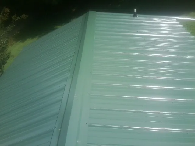 New green metal panels meeting at the ridge of a roof — Flat Roof Repair work by our crew in Mukilteo