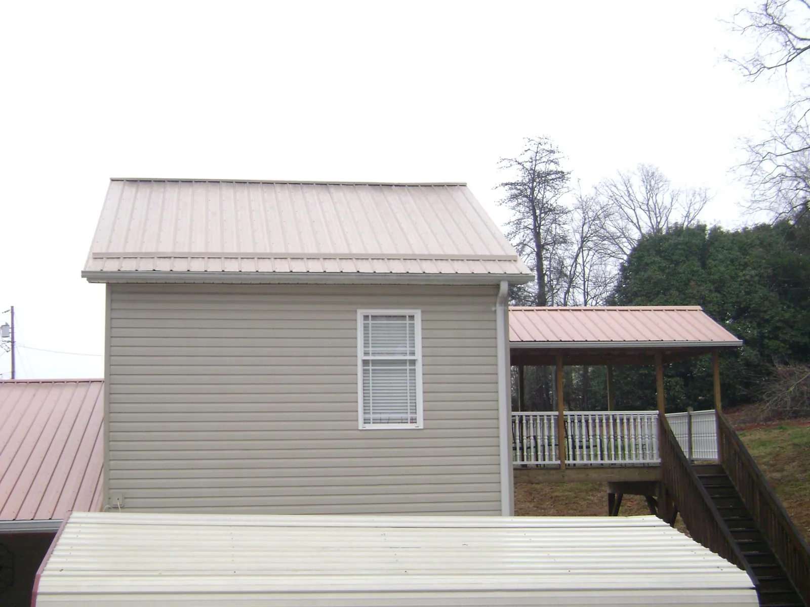 Tan metal roofs on a two story addition and attached porch, from a Roof Replacement job in Mukilteo
